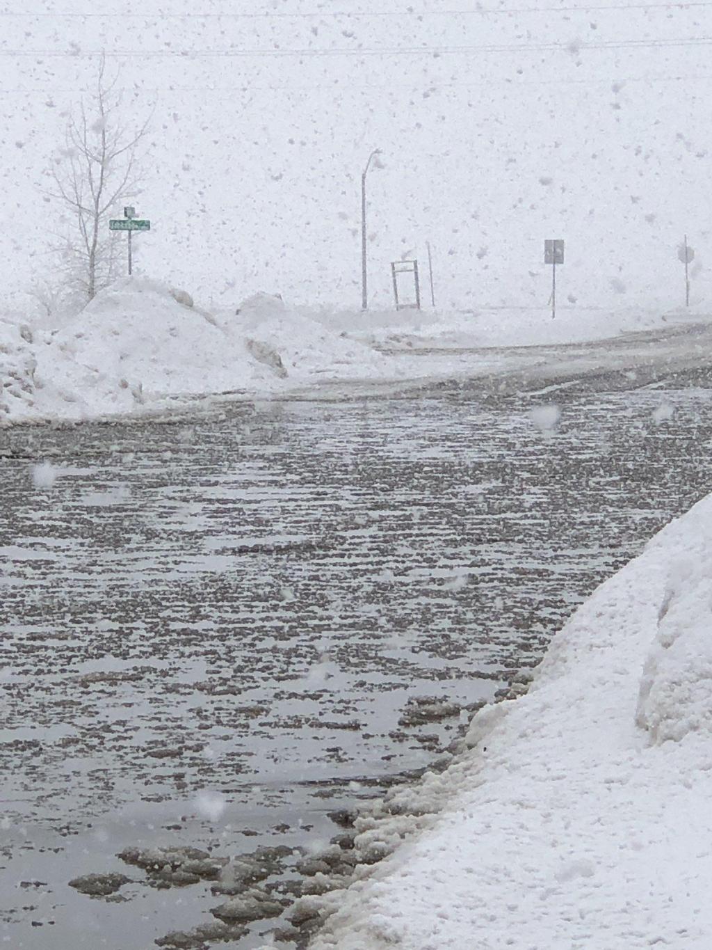 Snow falling into flooded street in southeast Sioux Falls