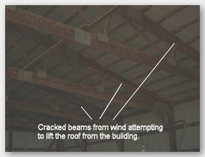 Photo of cracked roof trusses from wind attempting to lift roof from the building.
