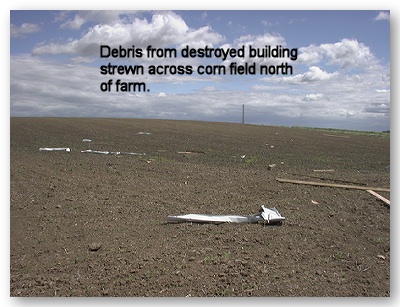 Photo of debris from destroyed building strewn across corn field north of farm.